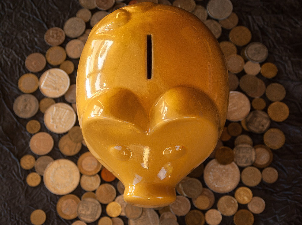 Yellow piggy bank with coins beneath