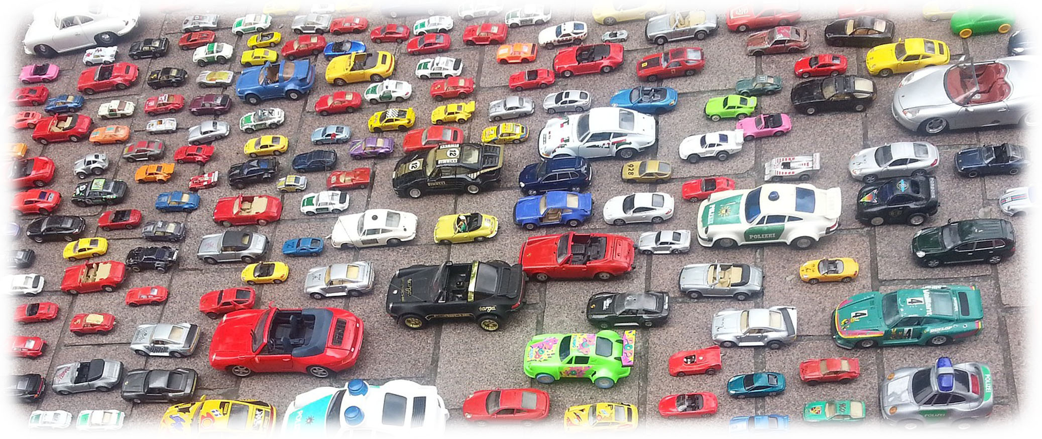 Close-up of a variety of toy cars arranged outside on stone