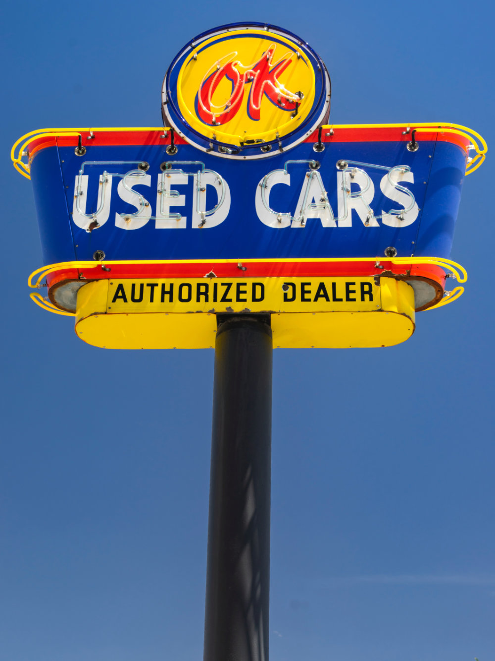 Classic blue and yellow tall sign that reads "Used Cars Authorized Dealer"