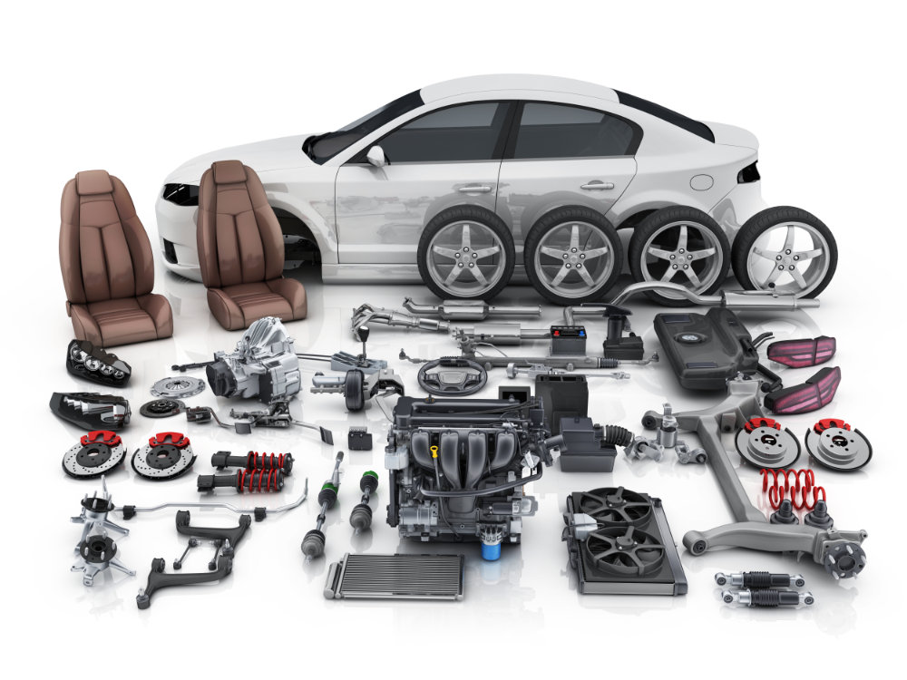 Disassembled white car with its various parts and seats sitting outside the vehicle