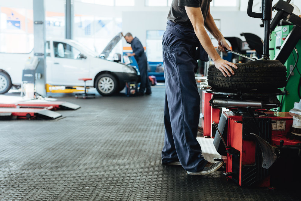 car maintenance worker dressed in blue working near tire in Canadian repair shop