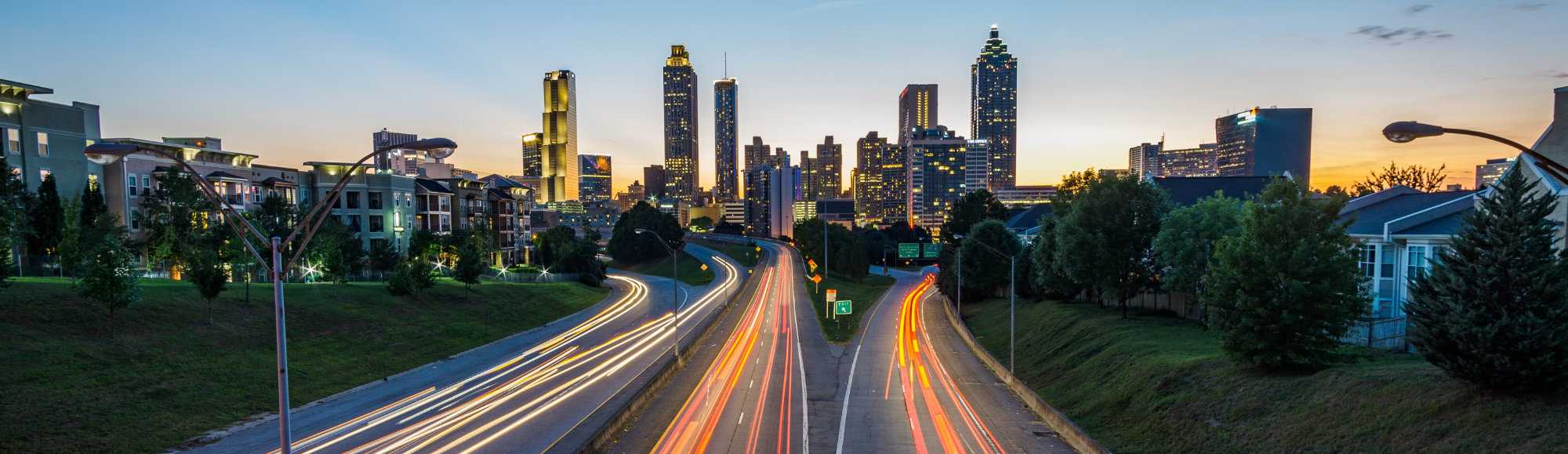 Time-lapsed, panoramic skyline shot of bustling city with busy highway in foreground