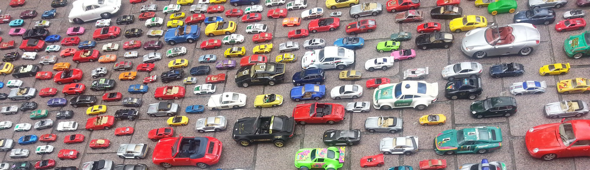 Collection of miniature toy cars arranged outdoors on stone